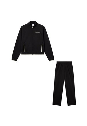 Zwarte ritssluitingjack met raglanmouwen en witte accenten, gecombineerd met bijpassende zwarte broek met een elastische tailleband.