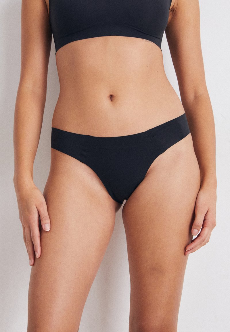 Melnas bikini apakšda ar gludu, matētu tekstūru. Iezīmē hipster griezumu un minimālu pārklājumu, radīta ērtībai un stilam.