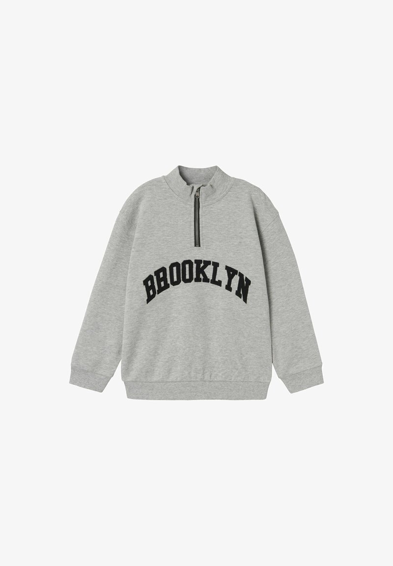 Sweatshirt gris avec un col montant, fermeture éclair noire et "BROOKLYN" imprimé en lettres noires en gras sur la poitrine. Tissu doux, coupe décontractée.