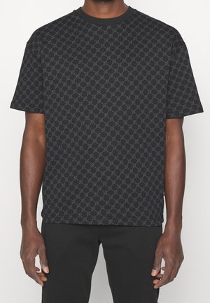 Black short-sleeve t-shirt featuring a textured pattern of interlinked circles. Round neckline and relaxed fit. Smooth cotton blend material.