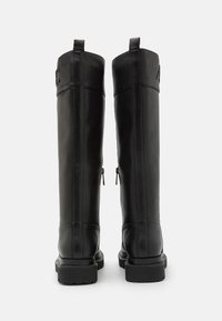 Botas altas de piel negra con una textura suave, que cuentan con dos cremalleras laterales y una suela gruesa. Diseño resistente con acentos mínimos.