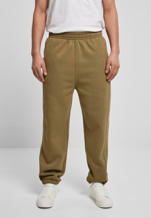 Olive green jogger pants with an elastic waistband and cuffs, featuring side seams and a soft texture, paired with white sneakers.