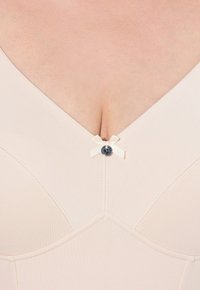 Lichtbeige bh met een V-hals ontwerp, met een kleine decoratieve strik en een blauwe knop in het midden, gemaakt van gladde stof.