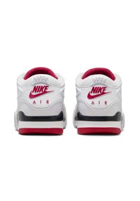 Scarpe da ginnastica Nike bianche con accenti rossi e suola nera. Presentano una parte posteriore testurizzata, un logo prominente e un colletto imbottito per il comfort.