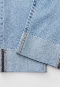 Tessuto in denim azzurro chiaro con sfumature diverse sui bordi. Presenta cuciture visibili e accenti bicolore, comprese strisce blu scuro.