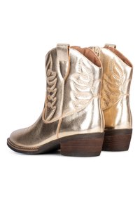 Zlaté kovbojské boty s texturovaným povrchem, zdobené listovými vzory a stohovaným dřevěným podpatkem. Boční zip pro snadné obouvání.