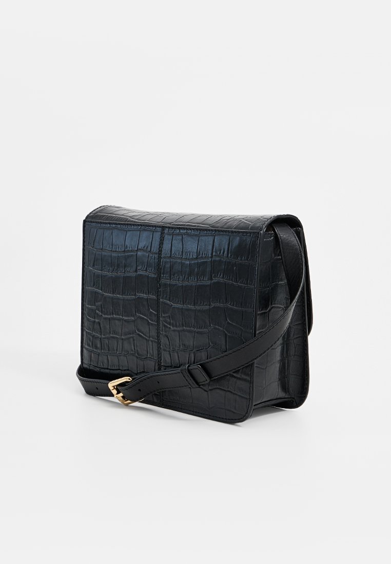 Czarna torebka crossbody z ekoskóry o fakturze krokodyla, prostokątna, z regulowanym paskiem i złotymi odmianami wykończenia.