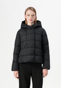 Casaco quimono preto com capuz, apresentando um design reticulado em quadrados, mangas longas e uma silhueta cropped. Textura suave e acabamento brilhante.