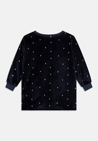 Mörkblå sammets långärmad topp med vita diamantformade mönster, ribbad rund nacke och figurnära ärmmuddar. Mjuk textur, avslappnad passform.