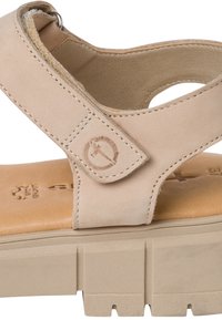 Sandale en cuir beige avec bride Velcro réglable et semelle intérieure rembourrée sur une semelle épaisse rainurée.
