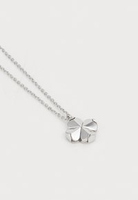 Colar de corrente prateada com um pendente em forma de trevo, com um acabamento polido e quatro secções de folhas simétricas. A textura é suave.