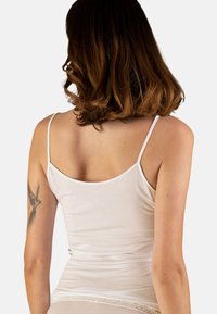 Light beige camisole with thin straps, smooth fabric, fitted design, and a delicate lace trim along the hem.