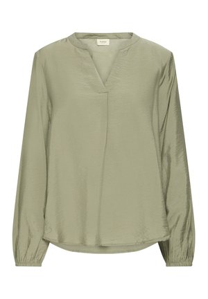 Bluză lungă cu mâneci lungi, de culoare verde deschis, cu guler în V și manșete elastice, proiectată cu un tiv ușor curbat și o textură de stofă moale și netedă.