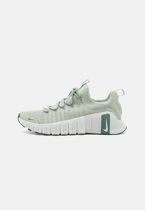 Baskets de sport vert clair avec une semelle épaisse blanche, des lacets et un logo Nike sur la semelle intermédiaire, présentées de profil sur un fond blanc.