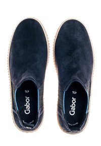 Marineblaue Slippers aus Wildleder mit elastischen Seitenpanelen, beiger Gummisohle und hellblauen Akzenten an der Innenauskleidung.