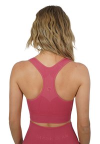 Soutien-gorge sport rosa con design a schiena nuotatrice, caratterizzato da un tessuto testurizzato e un accento con logo. Il materiale liscio e la vestibilità offrono comfort e supporto.