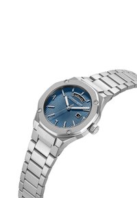 Reloj de acero inoxidable plateado con caja octagonal, esfera texturada azul, marcadores de hora plateados, indicador de fecha a las 6 en punto y pulsera de metal.