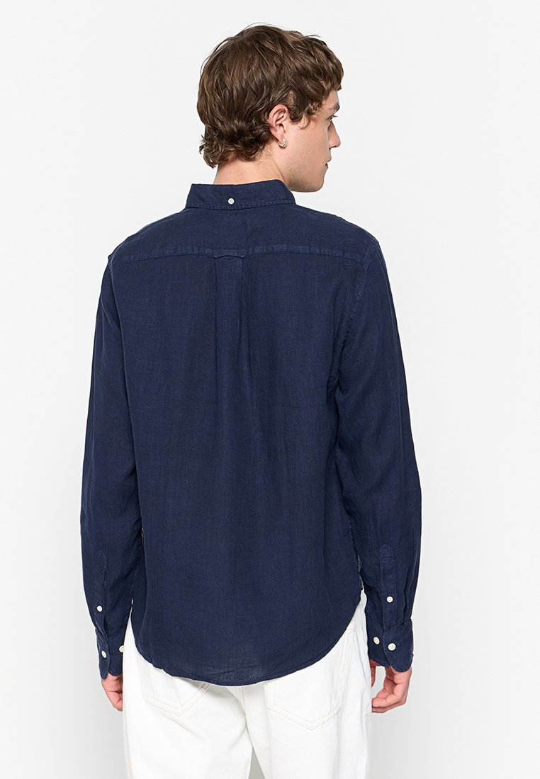 Camisa de manga larga en azul marino, con cuello abotonado, detalle en el canesú trasero, botones en los puños, confeccionada en tejido texturizado. Ajuste entallado.