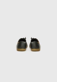 Scarpe in pelle nera con finitura testurizzata, forma arrotondata, suole in gomma e dettagli con lacci sul retro per una vestibilità sicura.