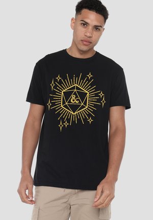 Black cotton t-shirt featuring a gold geometric design with an ampersand symbol, surrounded by starburst patterns and sparkles. Short sleeves.