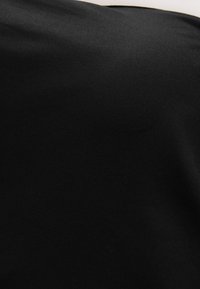 Sort stof med en glat, mat tekstur; fint ribbet mønster synligt. Materialet virker let og fleksibelt til forskellige anvendelser.