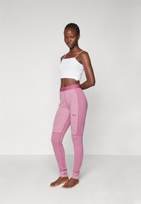 Szoros szabású, rózsaszín leggings függőleges csíkokkal és gyémántmintákkal, amelyeket egy széles, azonos árnyalatú rózsaszín derékpánt egészít ki.
