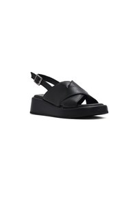 Sandali slingback in pelle nera con un ampio design a incrocio delle cinghie, suola a zeppa e fibbia metallica regolabile per una vestibilità sicura.