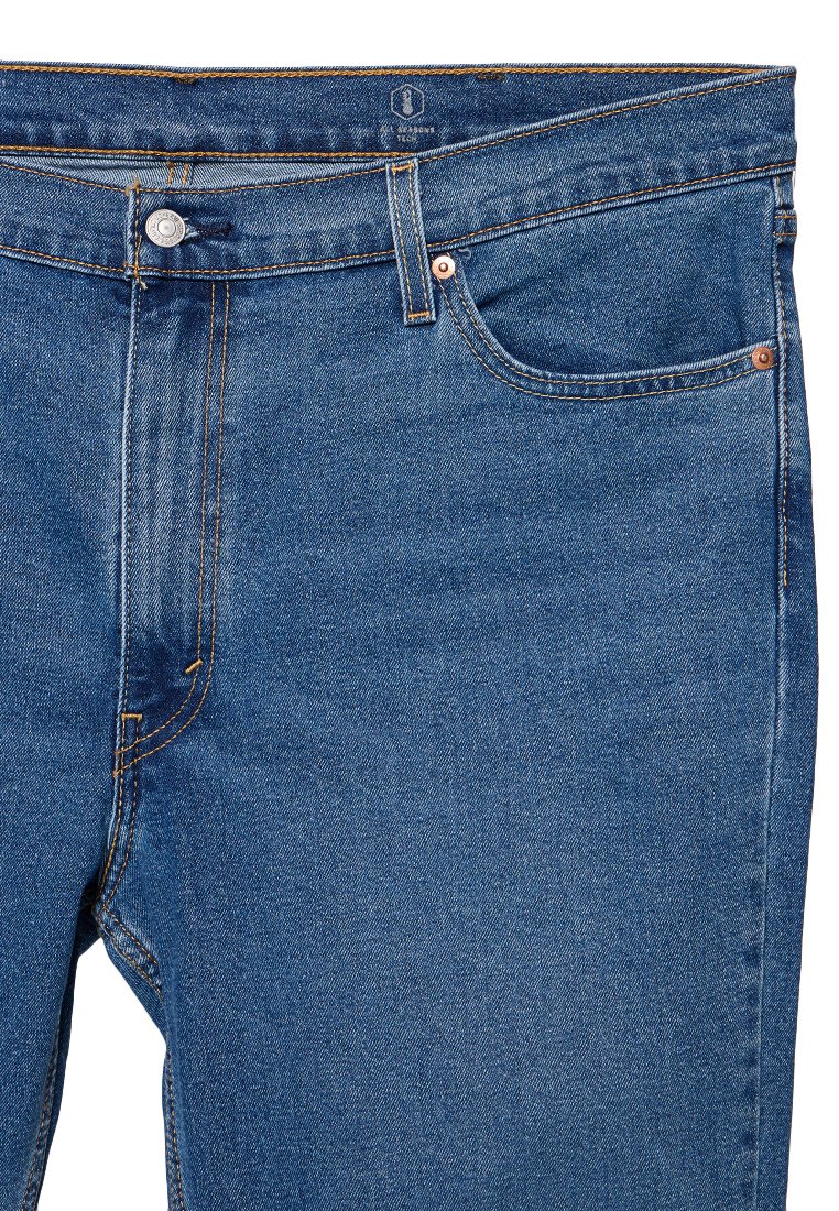 Blauwe spijkerbroek met een geknoopte tailleband, lussen voor een riem, voorzakken en zichtbare oranje naden tegen een witte achtergrond.