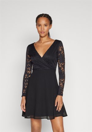 Black dress with a textured lace bodice and long lace sleeves; flared skirt with a smooth finish; V-neckline.