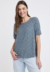 Kortärmad, teal blommig topp med rund halsringning. Har ett mönstrat design i rosa och vitt. Lättviktsmaterial, avslappnad passform.