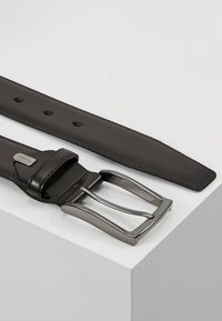 Cintura in pelle marrone con fibbia argentata opaca, dotata di una texture liscia e numerosi fori di regolazione lungo la cinghia.