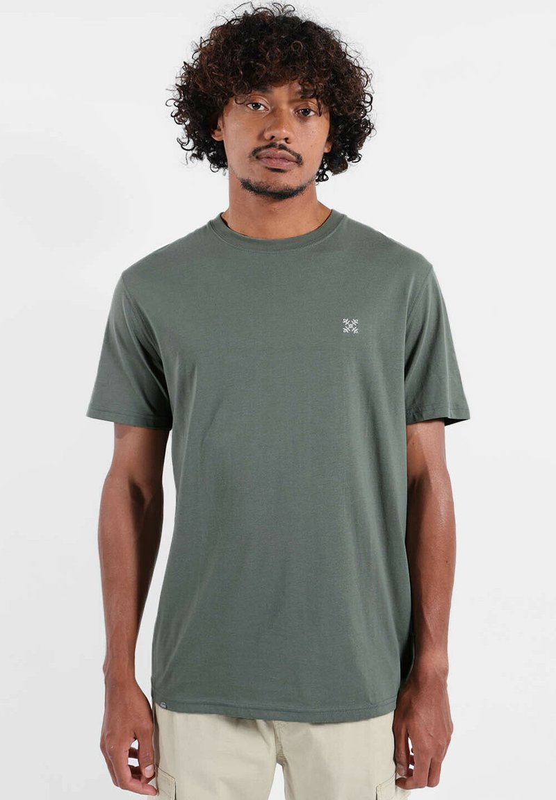 T-shirt à manches courtes vert olive en coton, avec un col rond et un petit logo blanc sur la poitrine. Texture lisse.
