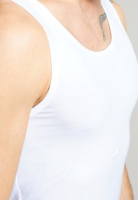 Weißes Baumwoll-Tanktop mit enganliegendem Design, ausgestattet mit einem runden Ausschnitt und glatter Textur. Der figurbetonte Schnitt betont die Körperform.