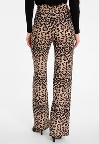 Luipaardprint, hooggetailleerde, uitlopende broeken in beige en zwart. Zachte textuur met een opvallend dierenpatroon. Draag met zwarte hakken.