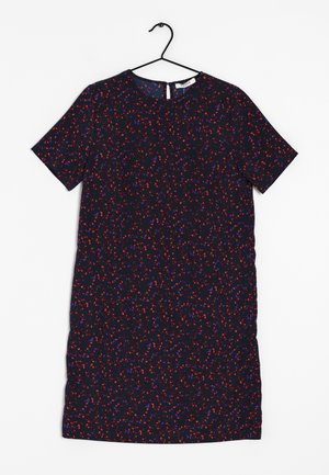 Robe courte à manches courtes, longueur genou, de couleur foncée avec un motif tacheté rouge et bleu, col rond, suspendue à un cintre en fil noir sur fond blanc.