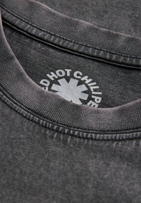 Mørkegrå t-shirt med rund halsudskæring, med synlige sømme og et trykt logo inden i kraveområdet. Blød stofstruktur.