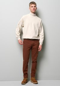 Creatieve turtleneck sweatshirt, gecombineerd met slanke bruine broek en tan veterschoenen. Zacht materiaal met een ontspannen pasvorm. Eenvoudig ontwerp.