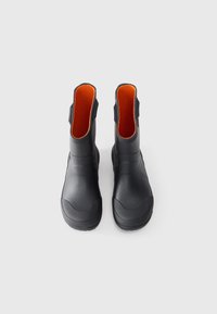 Bottines noires en caoutchouc texturé, dotées d'un intérieur orange, d'un bout arrondi et de languettes de chaque côté pour un enfilage facile.