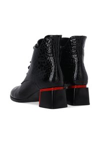 Černé kotníkové boty vyrobené z texturované kůže s hadím vzorem. Vybavené šněrováním vpředu a blokovými podpatky zvýrazněnými červenou barvou.