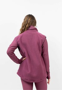 Fleece vest in diep paars met een hoge kraag, gestructureerd oppervlak en gebogen zoom. Draag het over een bijpassend longsleeve top en strakke broek.