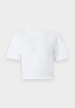 Λευκό κοντομάνικο cropped t-shirt με στρογγυλή λαιμόκοψη, τοποθετημένο επίπεδα σε ανοιχτόγριζο φόντο.
