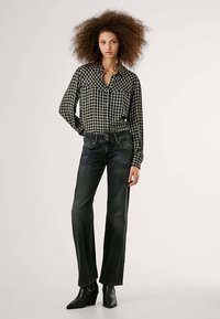 Mustvalge ruuduline pluus terava kraega, kombineeritud tumesiniste torupükside ja mustade pahkluu saapadega, luues juhusliku välimuse.