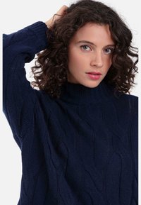 Marineblauer Strickpullover mit Zopfmuster, hohem Kragen und strukturierter Optik, ausgestattet mit langen Ärmeln und lockerem Schnitt. Weiches Wollmischgewebe.