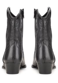 Stivaletti in pelle nera con punta leggermente appuntita, dotati di cuciture decorative e cerniere laterali, poggiati su un tacco basso e spesso.