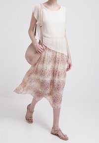 Kevyt kerma valkoinen yläosa, jossa on lyhyet hihat, kerroksittain yllään ilmava persikanvärinen hame, jossa on oranssin ja sinisen sävyinen kukkakuvio.