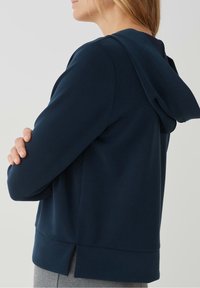 Felpa blu navy con cappuccio, tessuto morbido, vestibilità comoda e una fessura laterale all'orlo per maggiore comfort e movimento.