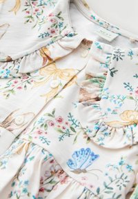 Ziedu raksta kleita no viegla auduma ar volānu apkakli un pogu aizdari, rotāta ar daudzkrāsainiem ziediem un tauriņiem pasteļtoņos.