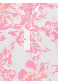 Blouse florale avec un fond blanc, ornée de grandes fleurs roses et corail, décolleté en V et texture de tissu douce.