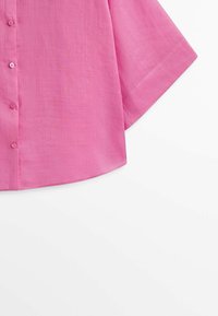 Chemise à manches courtes à boutons de couleur rose vif, confectionnée dans un tissu léger à la texture lisse et à la coupe décontractée.