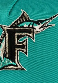 Turquoise fabric features an embroidered black "F" and a marlin design. Detailing includes silver and turquoise accents with a textured finish.